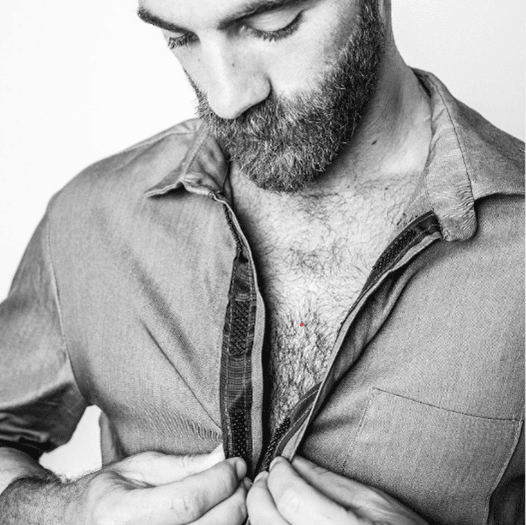 A bearded man putting on a shirt using inclusive velcro